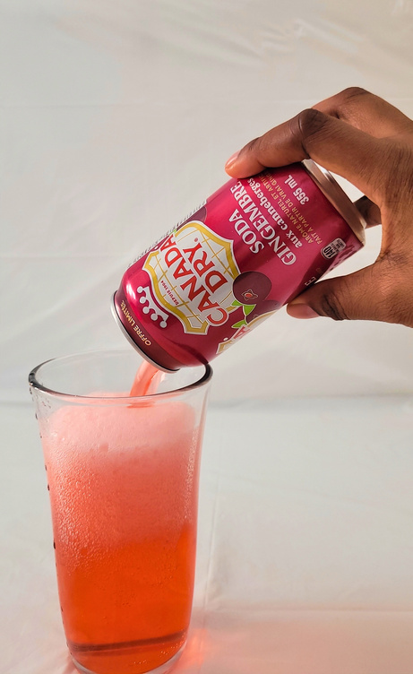 a ugc creator pours a can of soda into a glass