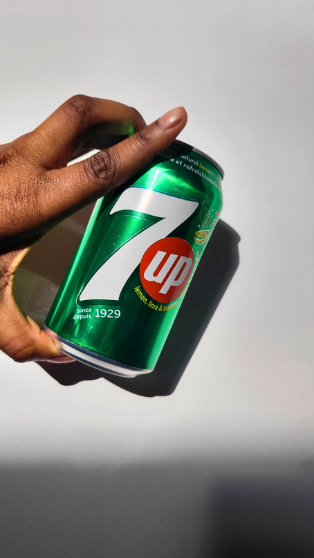 a person holding up a can of 7up