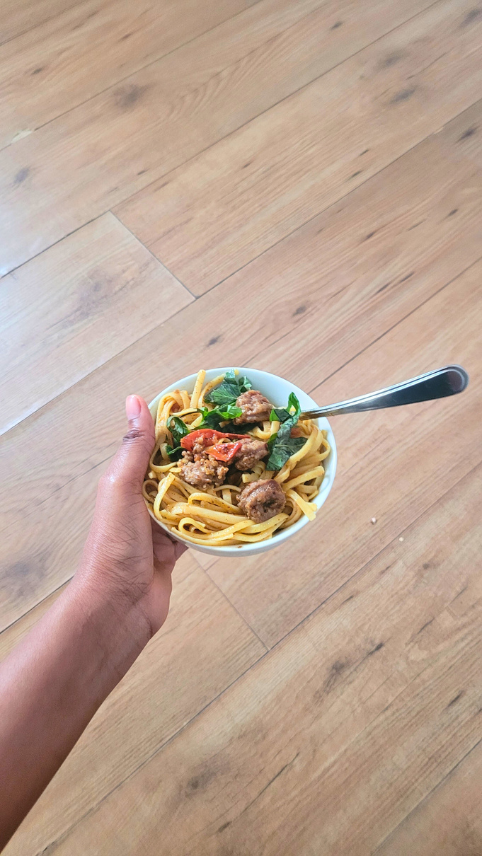 a ugc creator holding a bowl of pasta on a wooden floor